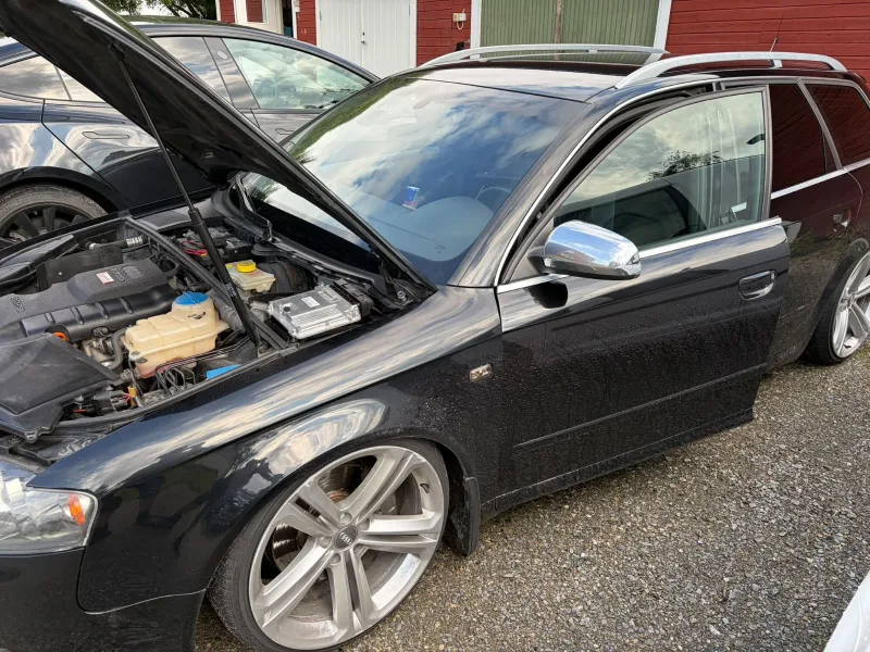 Bil med öppen motorhuv på gården
